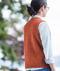 a woman wearing a sweater vest and jeans