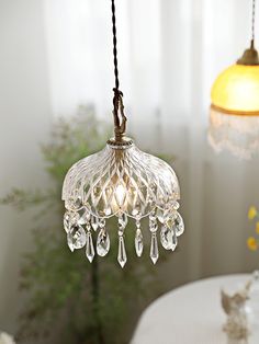 a glass chandelier hanging from a ceiling in a room with white walls and windows