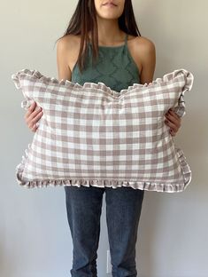 a woman holding a pillow with ruffled edges