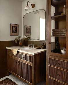 a bathroom sink sitting under a large mirror next to a wooden cabinet and counter top