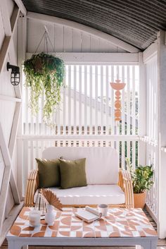 a white couch sitting on top of a wooden floor next to a table and potted plants