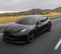 a black tesla car driving down the road