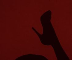 the shadow of a person's hand holding a cell phone in front of a red background