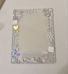 a mirror with snowflakes and hearts on it sitting on a table next to a pen