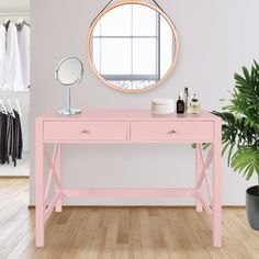 a pink desk with two drawers and a round mirror on the wall next to it