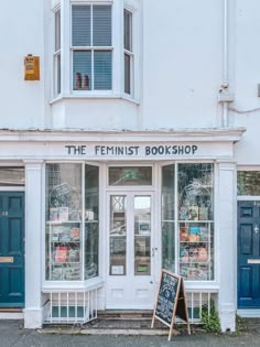 the feminist book shop is located in front of a white building with blue doors and windows