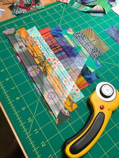 a pair of scissors sitting on top of a cutting board next to some pieces of fabric