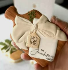 a hand holding a decorated cookie with the words home and an ornament on it