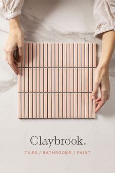 a person is holding a tile with the words claybook tiles / bathrooms / paint on it