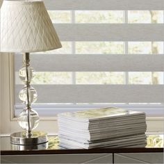 a lamp sitting on top of a table next to a stack of books and magazines