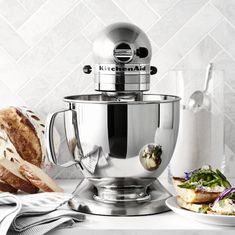 a kitchen aid mixer sitting on top of a counter next to bread and other food items