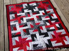 a red and black quilt on a wooden floor