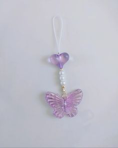 a purple and white butterfly ornament hanging from a string on a white wall