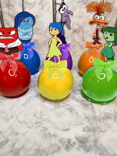 four vases with cartoon characters on them sitting on a marble counter top in front of an assortment of other decorative items