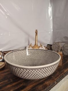 a white and black bowl sitting on top of a wooden table next to a bottle of wine