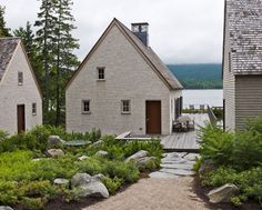 two small houses sitting next to each other in the woods near water and trees,