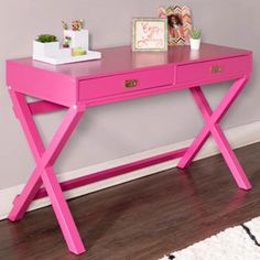 a pink desk with two drawers and a white rug on the floor next to it