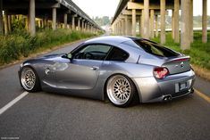 a silver sports car is parked on the side of the road near an overpass