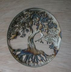 a metal plate with a tree on it sitting on top of a wooden table next to a wall