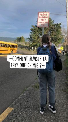 a person with a back pack standing in front of a school bus on the road