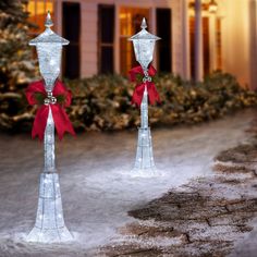 two silver candlesticks with red bows on them in front of a white house