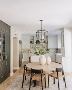 a dining room table with chairs and vases sitting on it's centerpiece