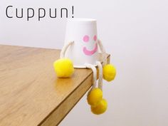 a white cup with yellow pom - poms hanging from it's sides