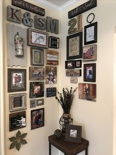 the wall is covered with many different pictures and framed photos, along with a vase filled with flowers