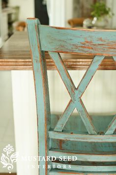 an old blue chair sitting in front of a wooden table