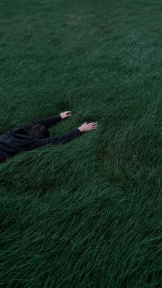 a person laying in the grass with their arms out