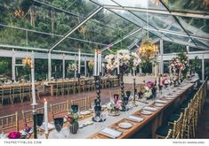 a long table is set up with flowers and candles for a wedding reception in a greenhouse