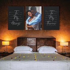 a bed with two pictures on the wall above it and flowers in front of it