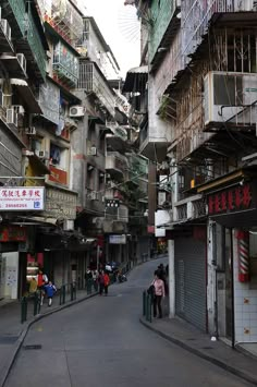 people are walking down the street in an alleyway with many balconies and apartment buildings