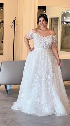 a woman in a white wedding dress standing next to a bench with her hands on her hips