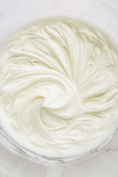 whipped cream in a glass bowl on a white surface