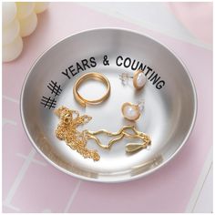 a silver plate with gold rings and other jewelry on it that says years & counting