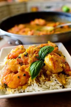 a plate of shrimp and rice with basil garnish