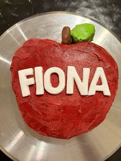 a red cake with the word fiona spelled out in white frosting on a silver plate