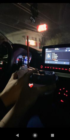 a person holding a game controller in their hand while driving through the street at night