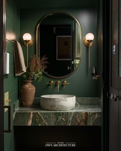 a bathroom with green walls and marble counter top, round mirror on the wall above the sink