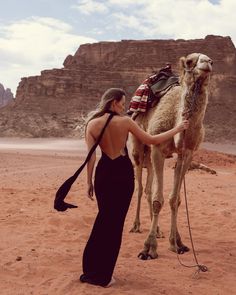 a woman is petting a camel in the desert