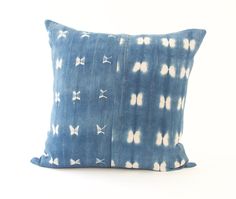 a blue and white tie dye pillow with bows on it, sitting on a white surface