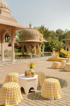 yellow and white striped tablecloths on tables in front of an ornate gazebo