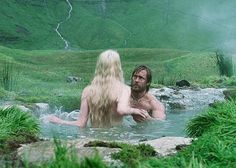 a man and woman are in a hot tub with water flowing down the hill behind them