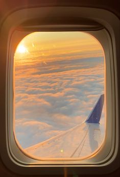 an airplane window with the view of clouds and sun in the sky from inside it