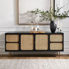 a black and gold sideboard with candles on it in front of a white wall