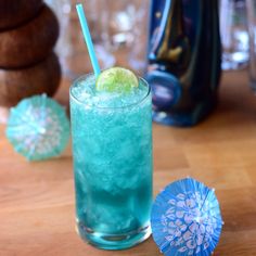 a blue drink with a lime on the rim and an umbrella in front of it