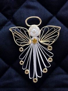 a metal angel ornament on a black quilted surface with gold trimmings