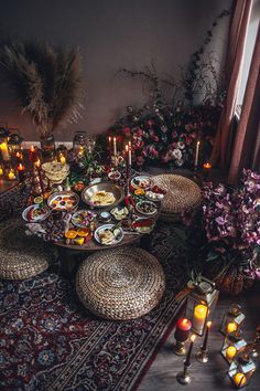 a table filled with lots of food on top of a rug next to candles and flowers