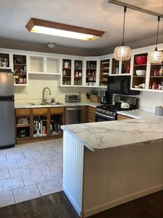 a kitchen with white cabinets and marble counter tops, an island in front of the stove